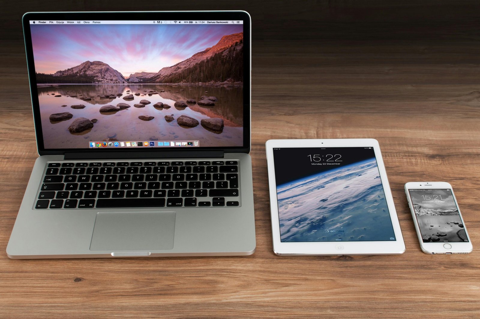 a macbook, ipad and iphone on a table next to one another